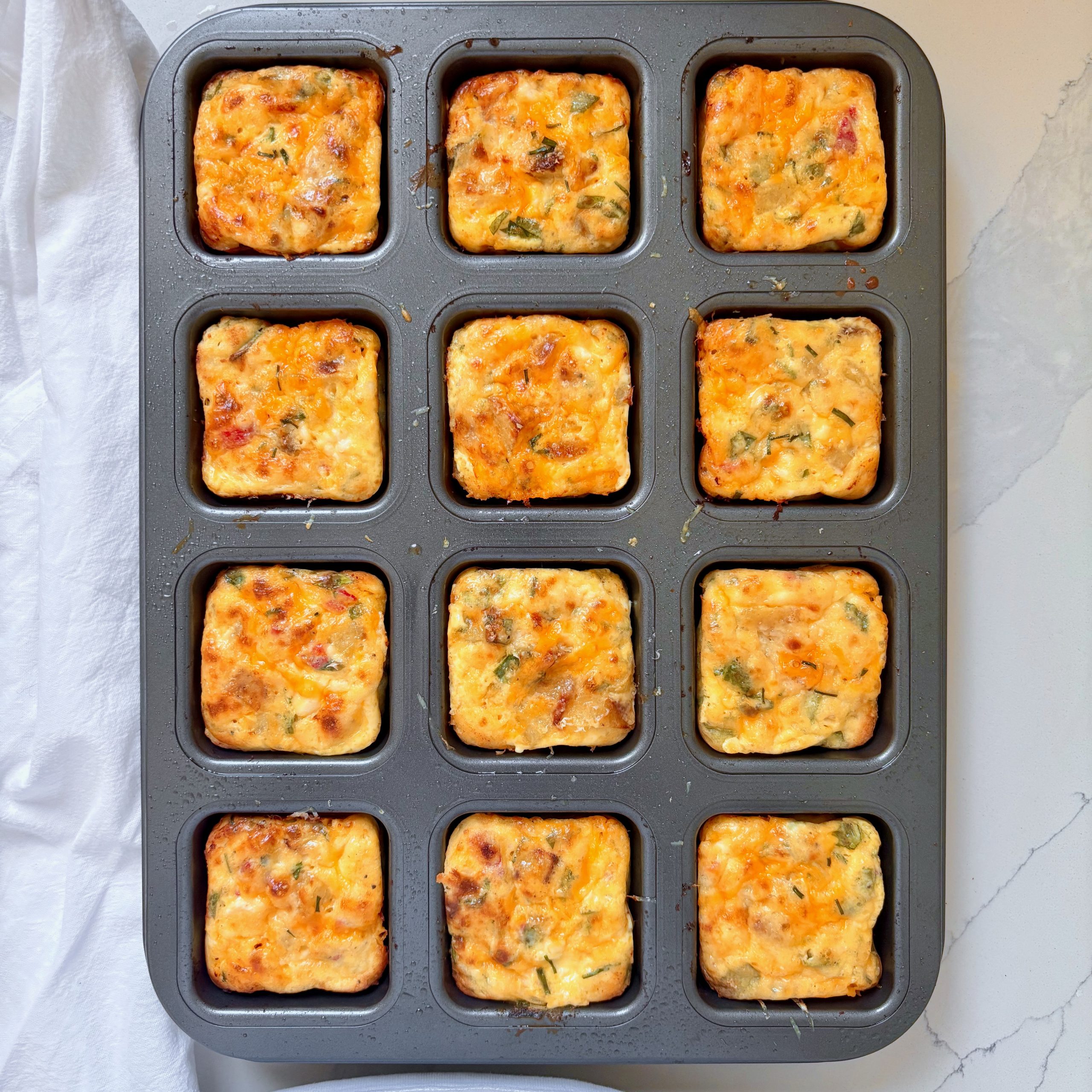 Golden cheesy veggie egg bites in muffin tin