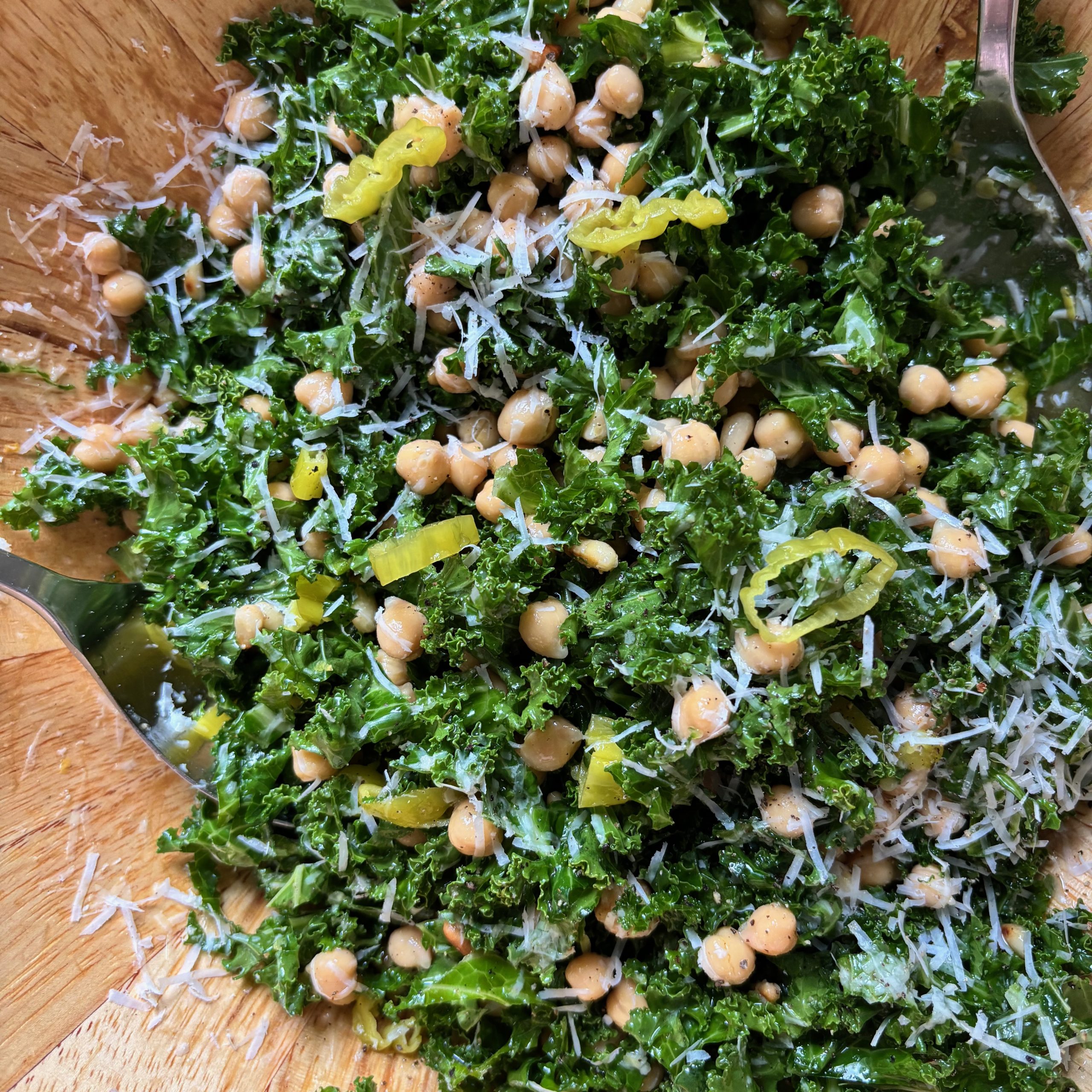 Overhead shot of serving bowl with kale and chickpea salad with parmesan cheese and lemon