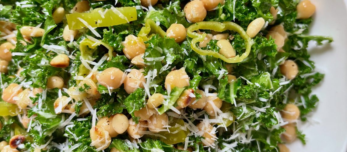 Bowl of kale salad with chickpeas, pepperoncini, and lemon parmesan dressing