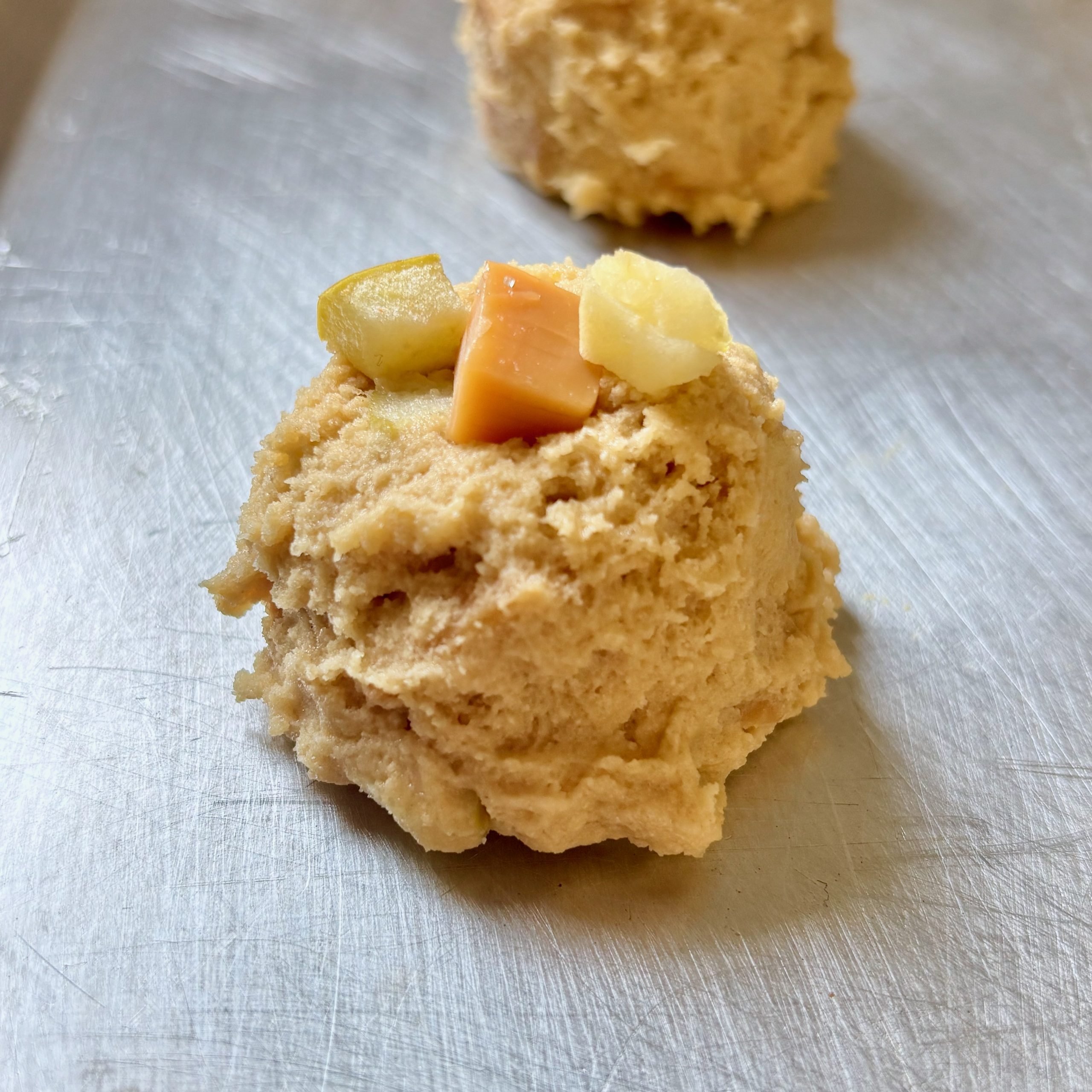 Cookie dough balls with caramel chunks and apple pieces before baking