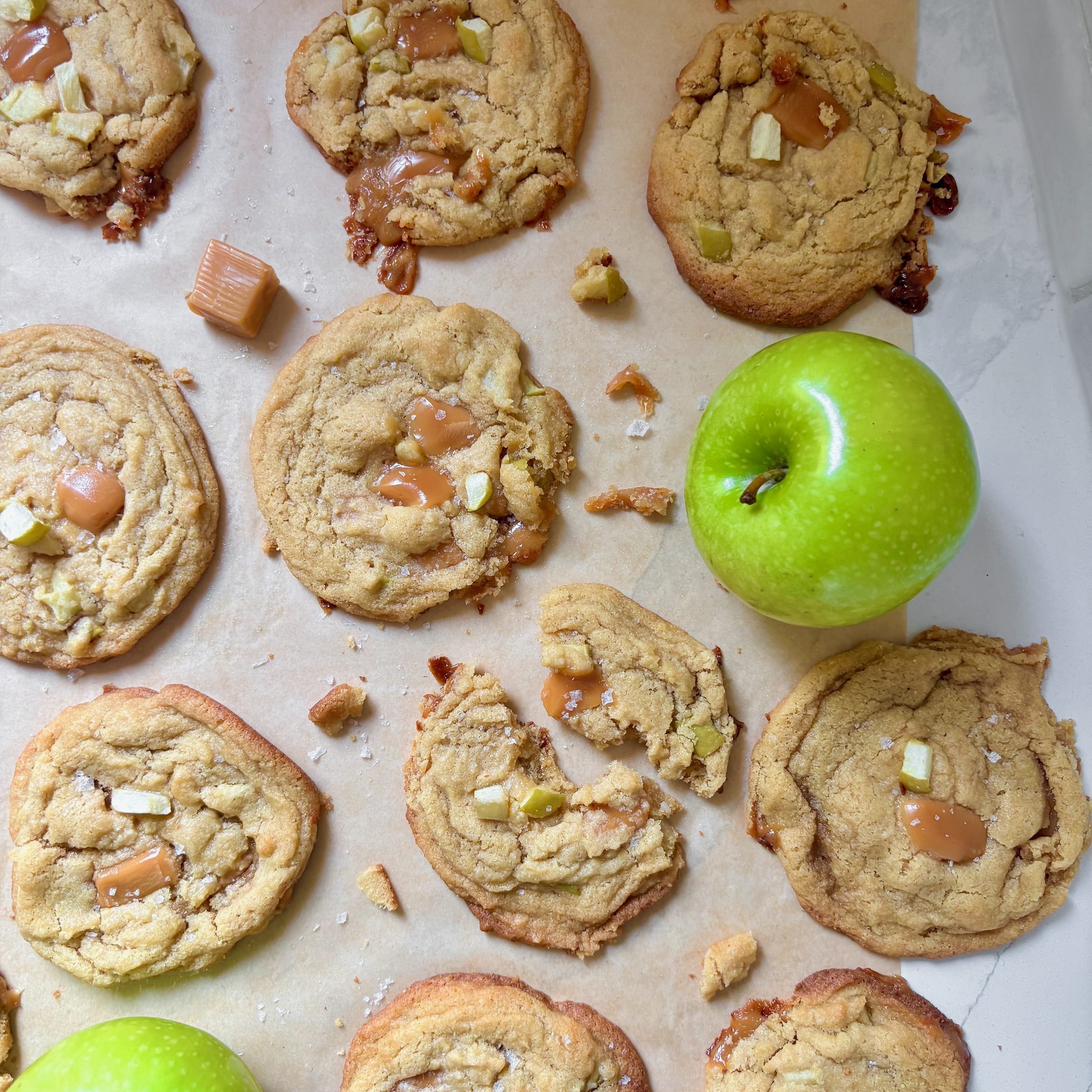 Overhead shot of fresh baked salted caramel apple cookies on a parchment-lined tray