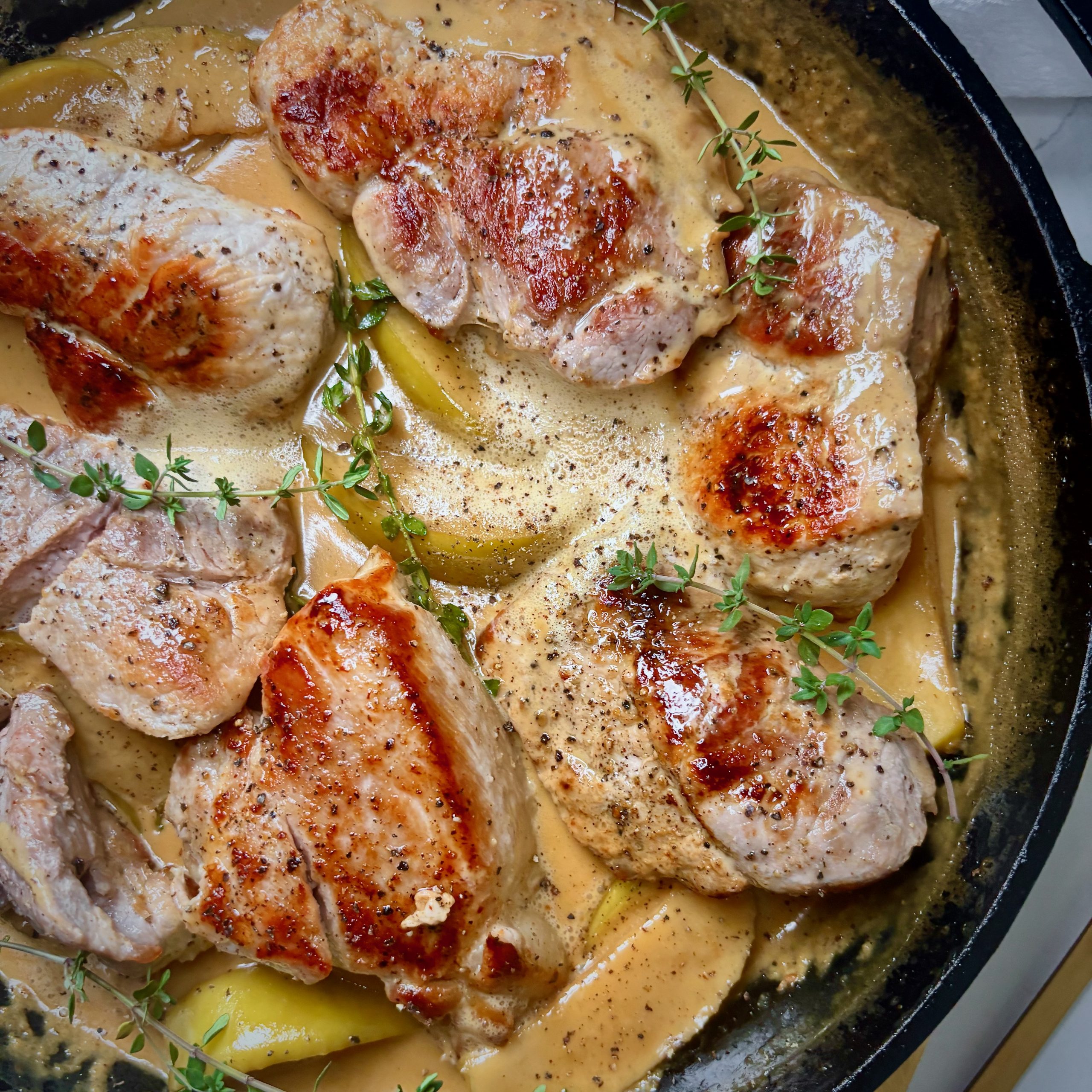 Close-up of sliced pork topped with miso maple cream sauce and fresh herbs