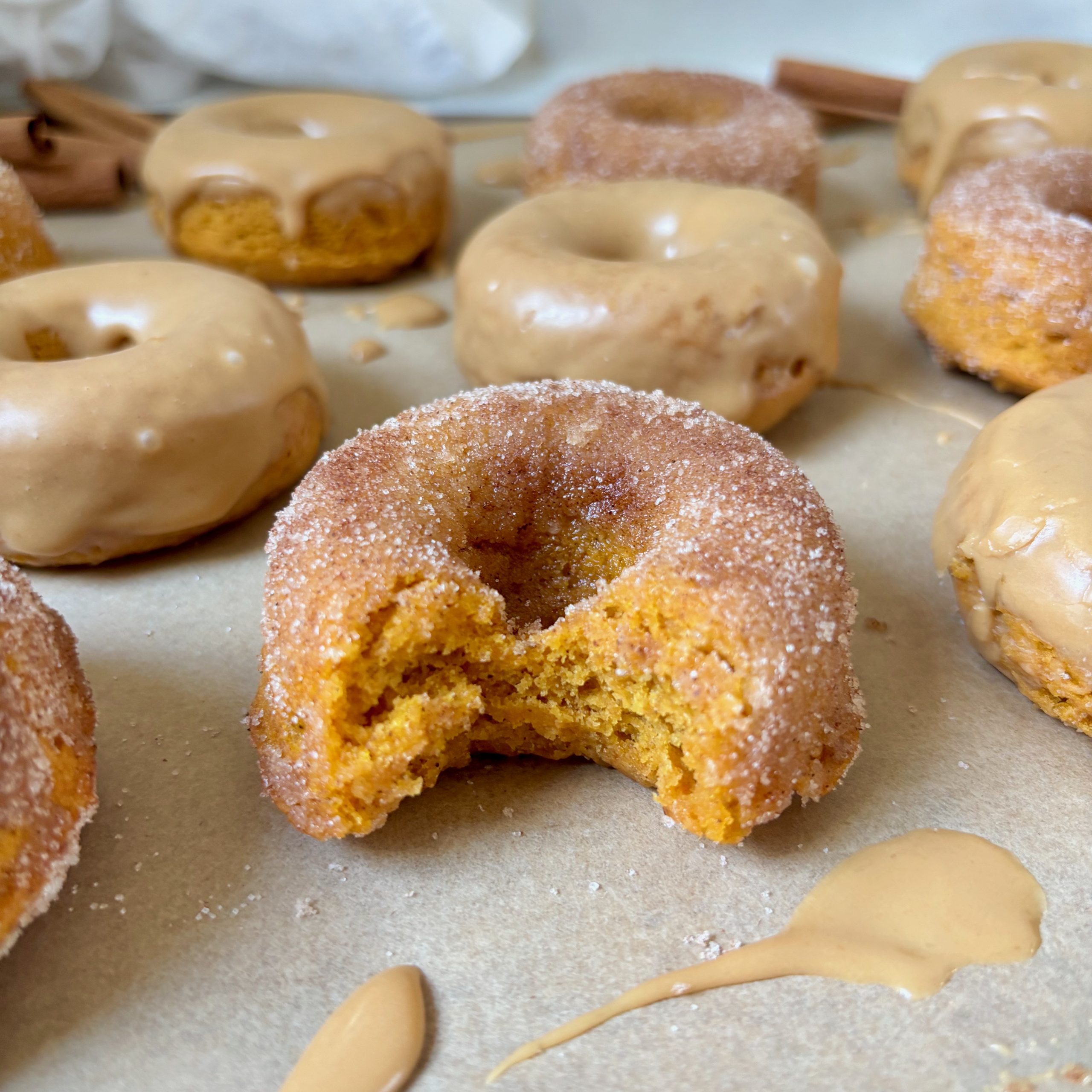 Bite out of pumpkin spice donut with cinnamon sugar topping