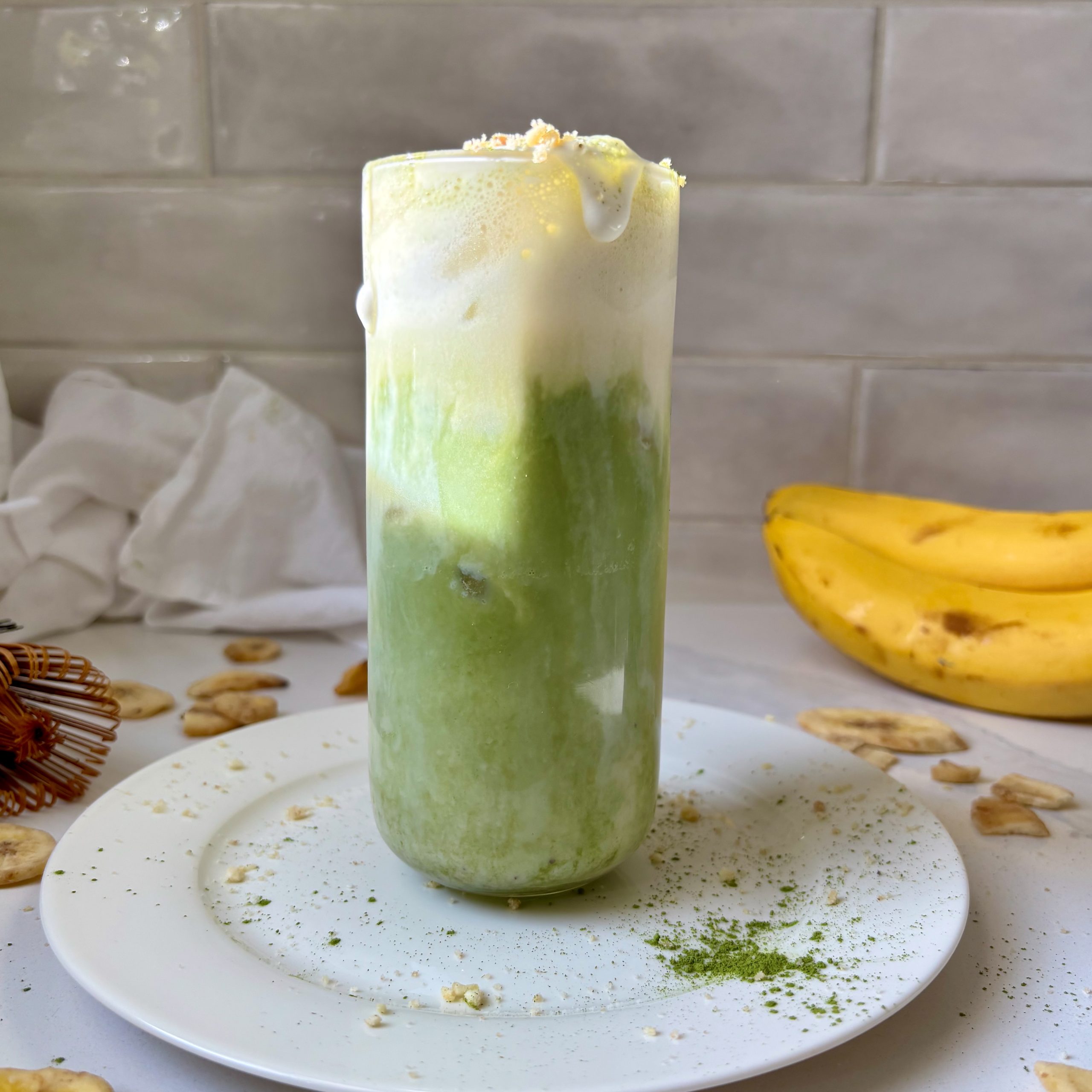 Banana Cream Matcha Latte with hand holding glass