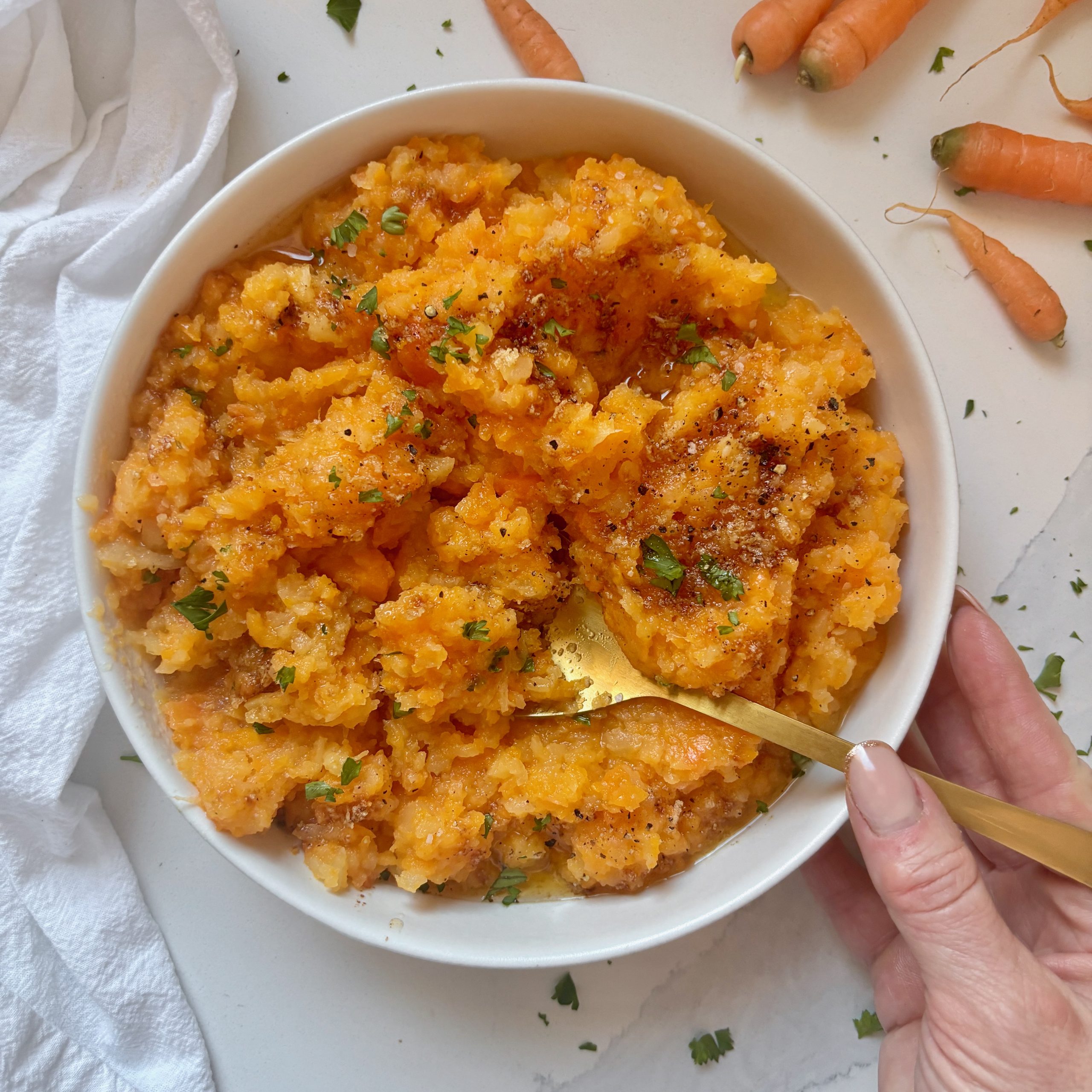 Garlic brown butter drizzled over a warm bowl of mashed rutabaga and carrots, garnished with fresh parsley.