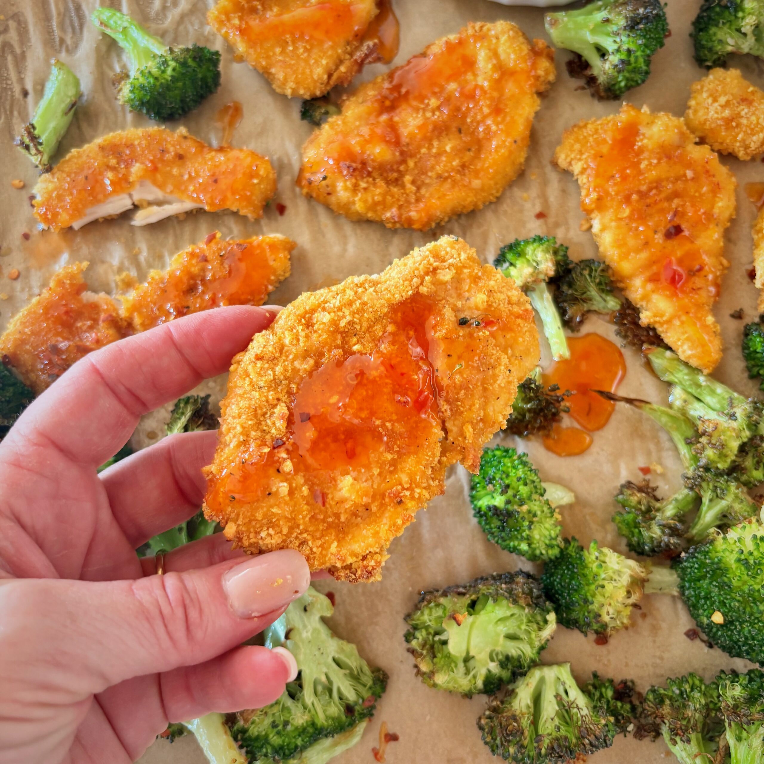 Hand holding cornflake chicken strip