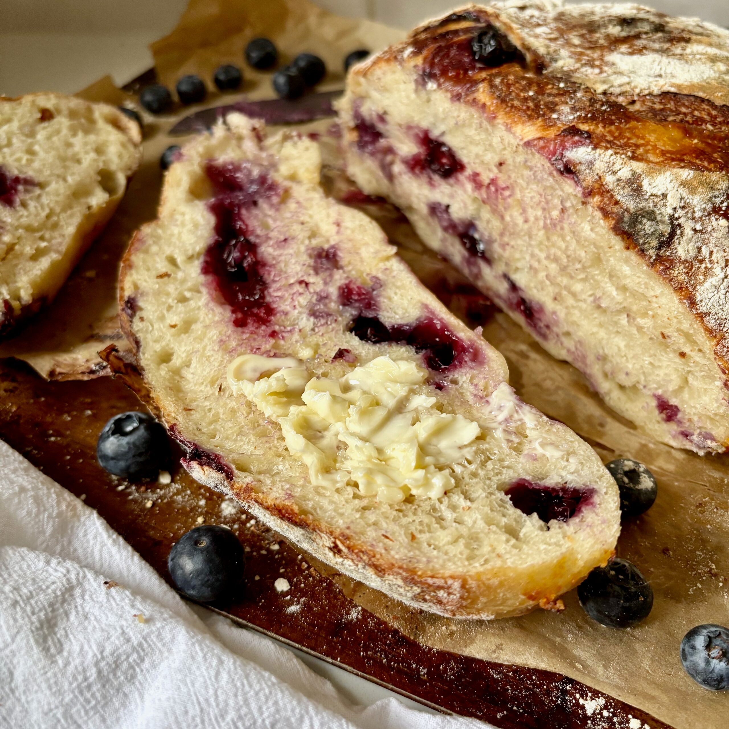 Thick slice of blueberry sourdough bread with white chocolate chips and melty butter