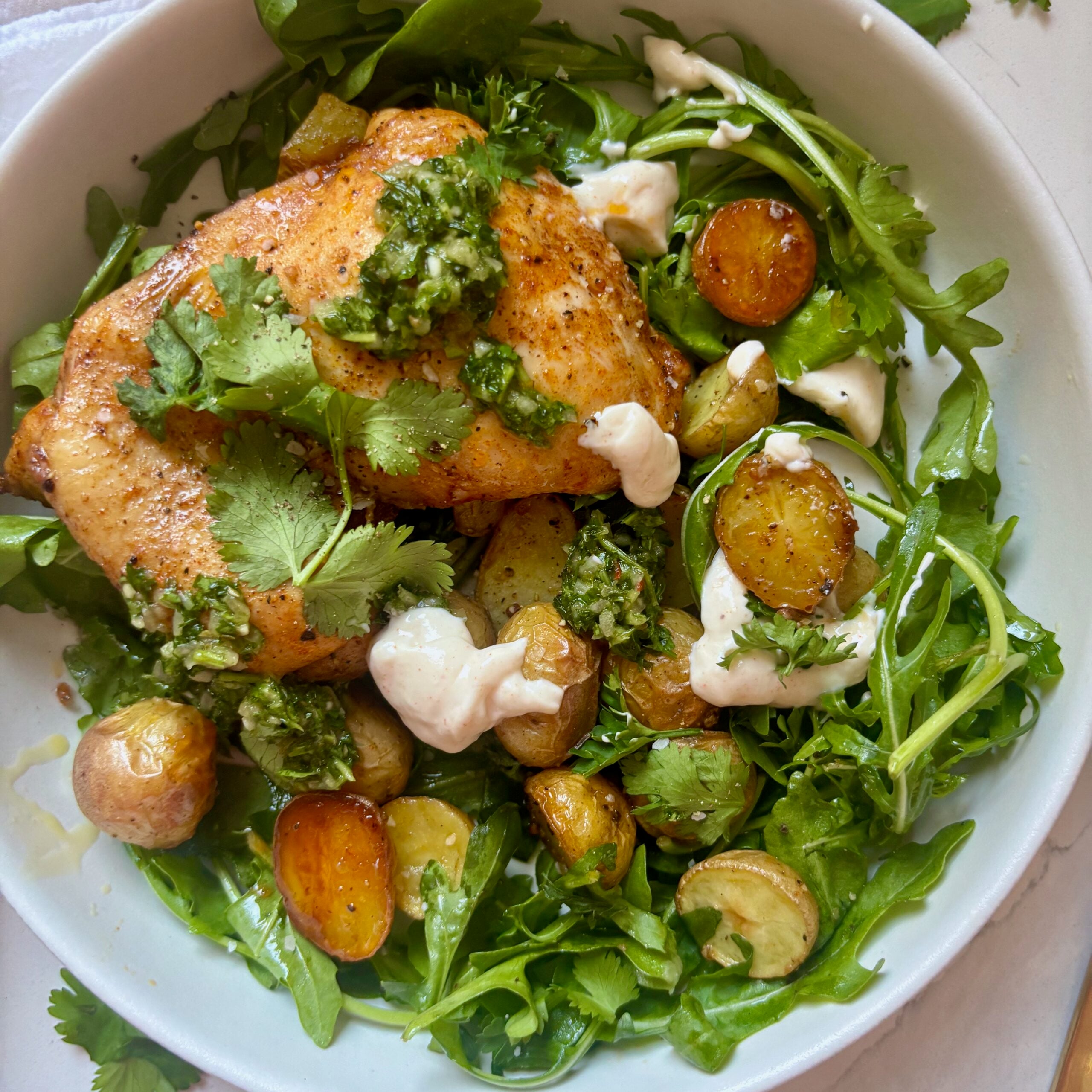 Juicy roasted chicken thighs with crispy potatoes and green chimichurri sauce