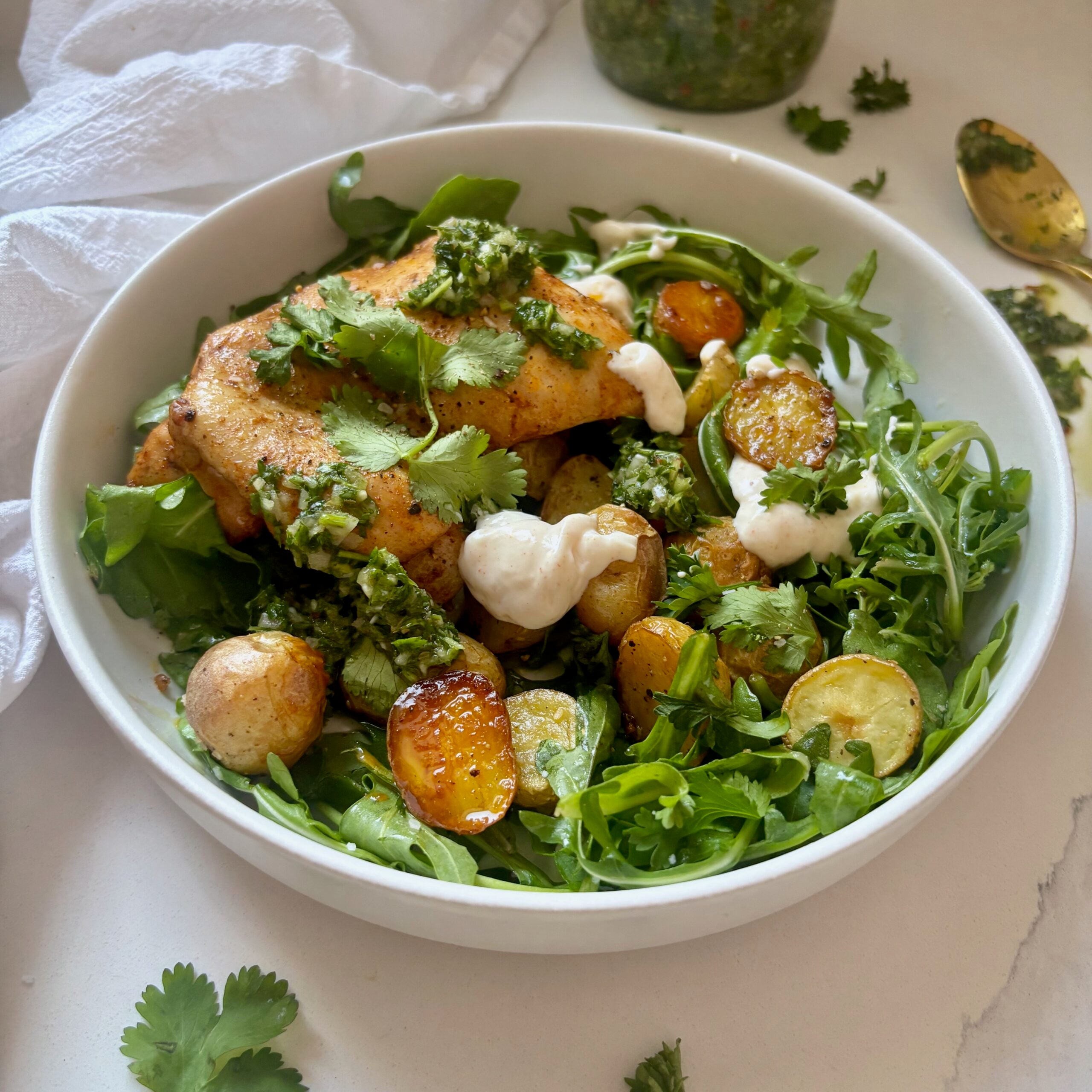 Chimichurri chicken and potatoes served over fresh arugula with yogurt aioli