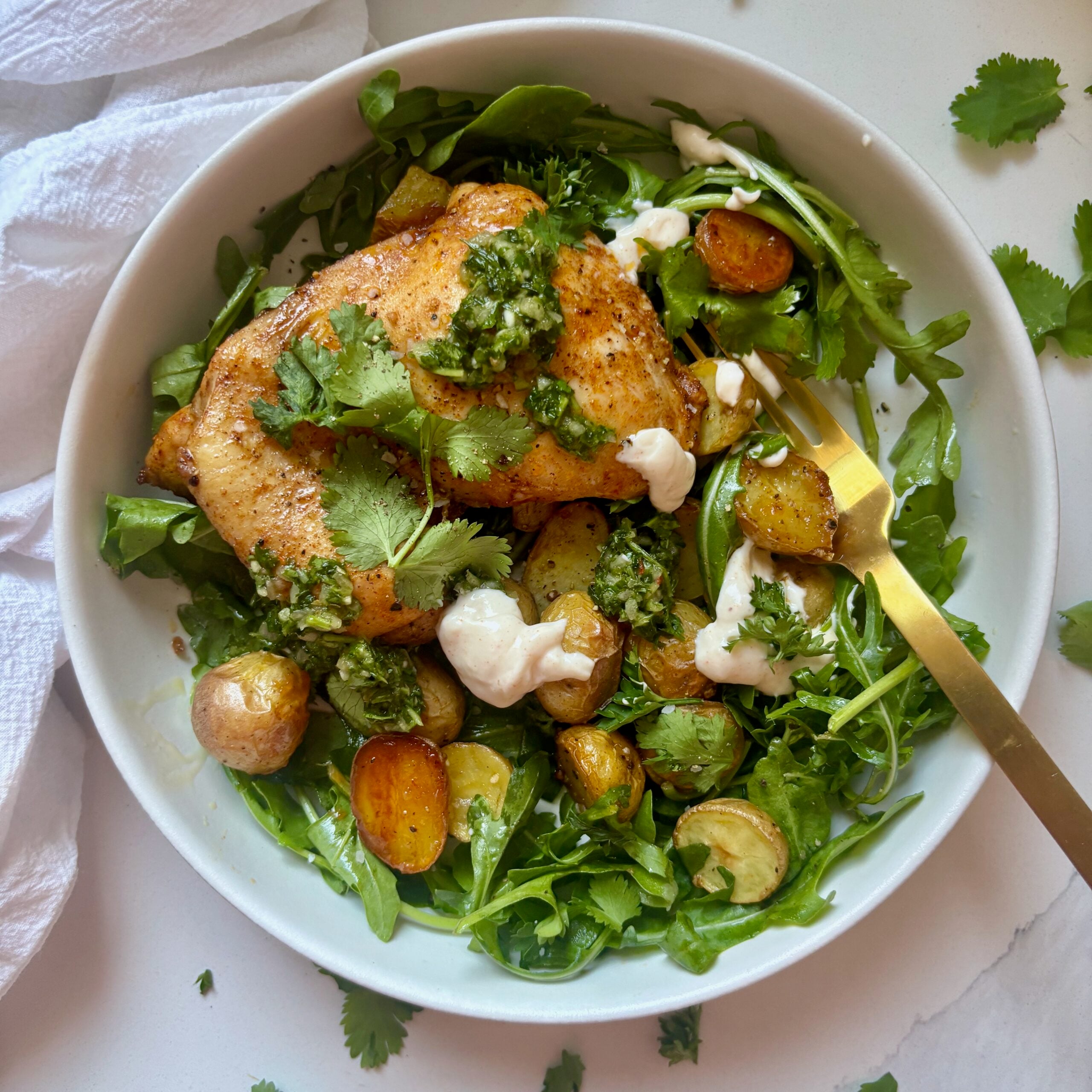 Plated chimichurri chicken with arugula, lemon, and creamy aioli drizzle