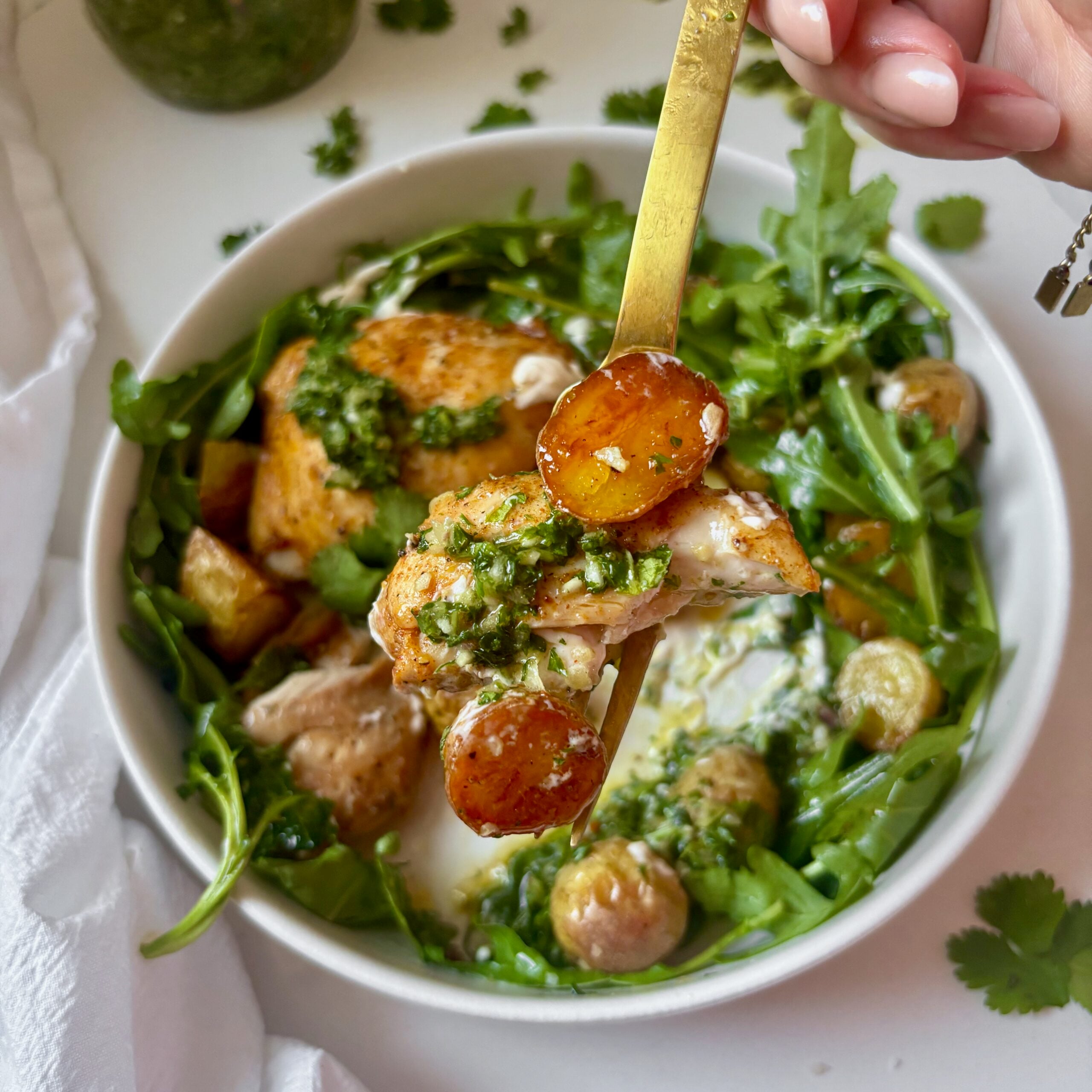 Fork full of chimichurri chicken with arugula, lemon, and creamy aioli drizzle