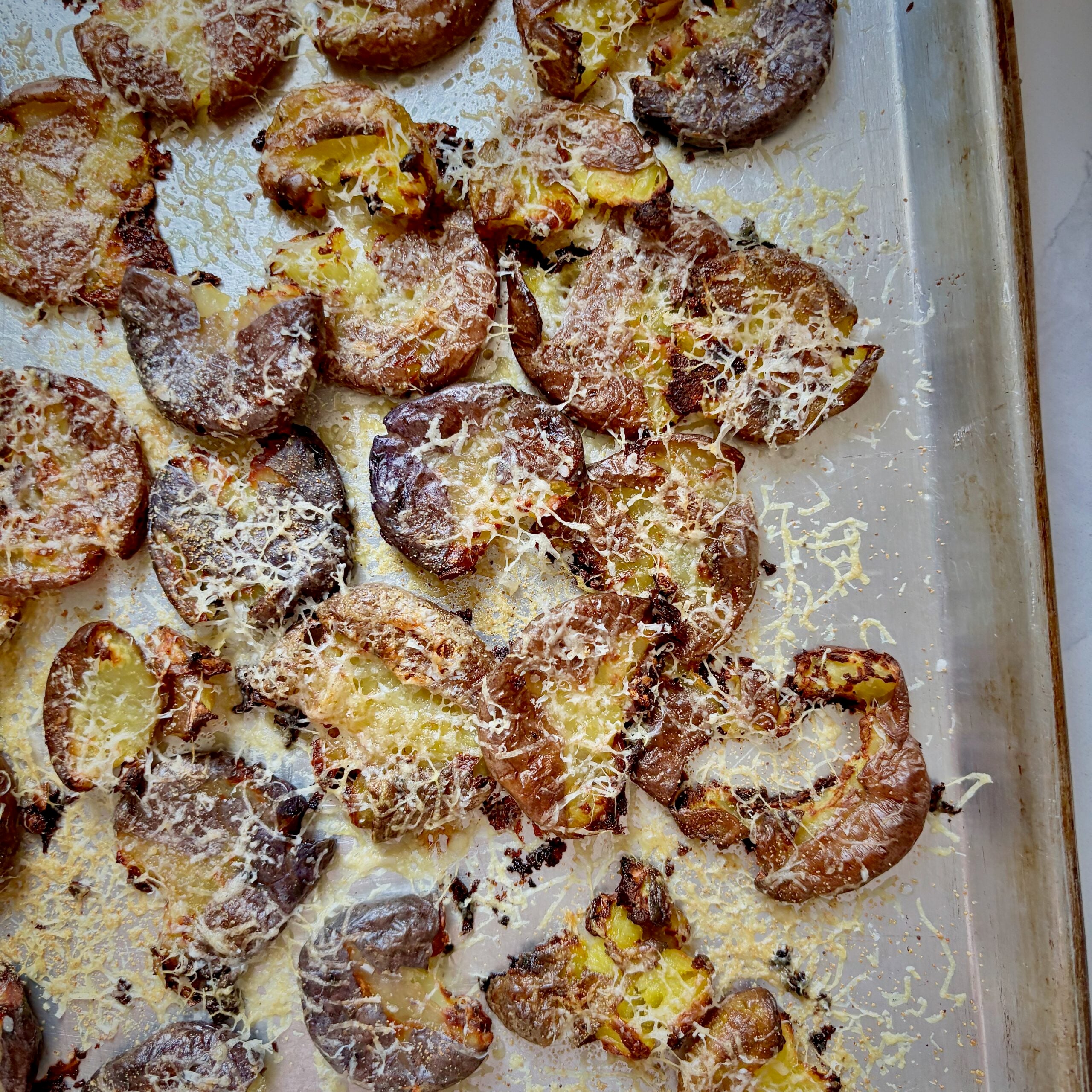 crispy smashed garlic parmesan potato croutons on sheet pan