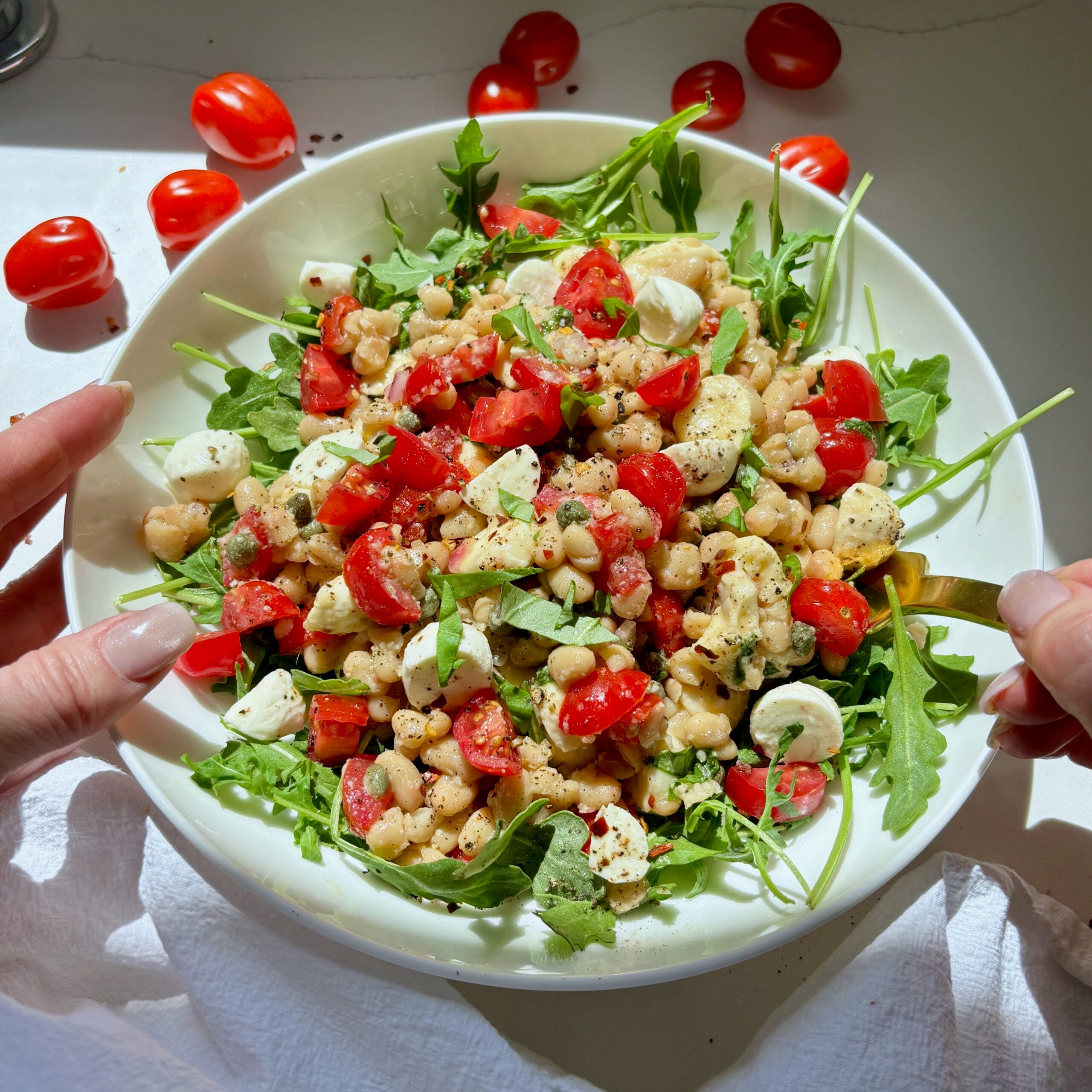Bowl full of marinated white bean salad with bocconcini and tomatoes.