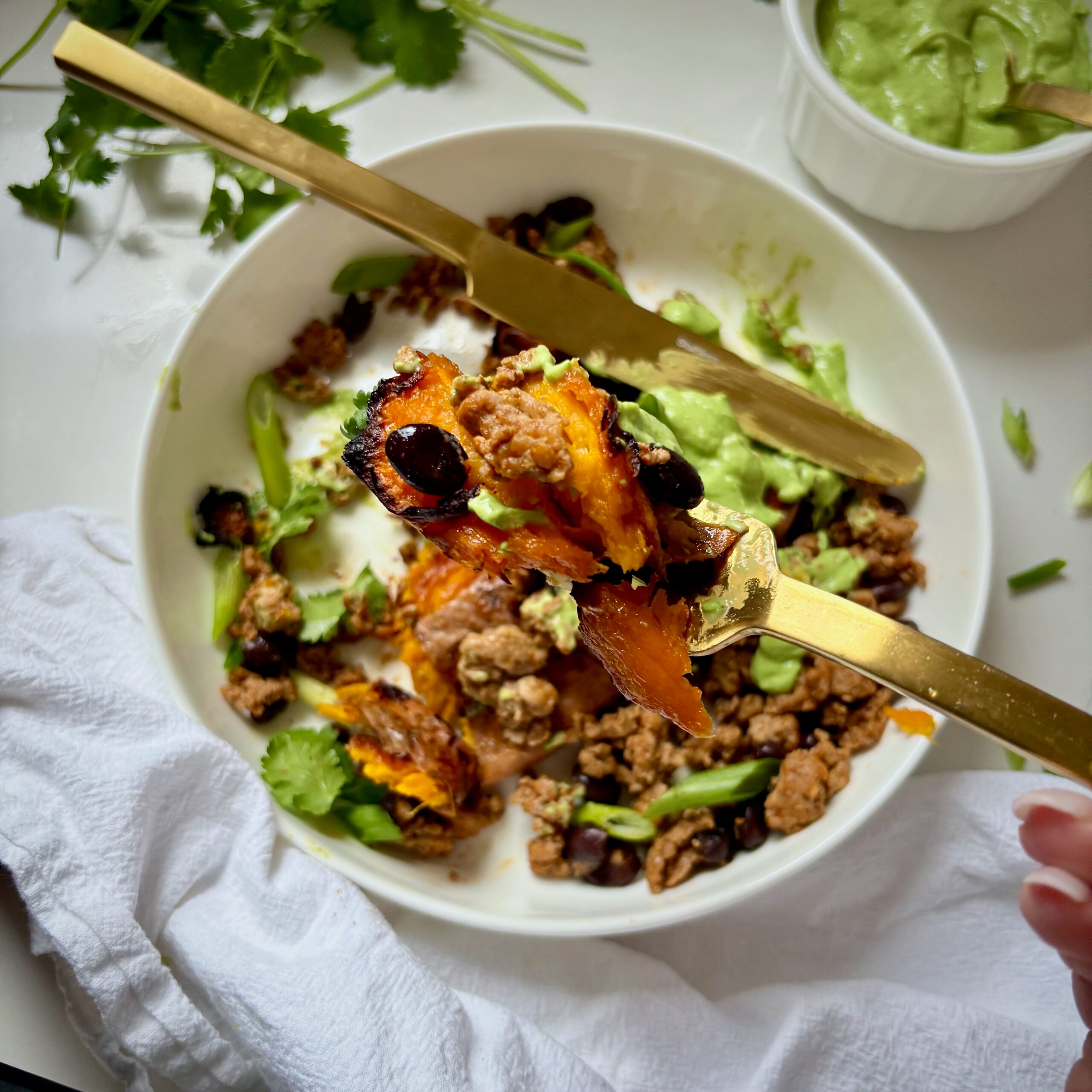Fork full of crisp roasted sweet potato with black beans, ground turkey and green sauce