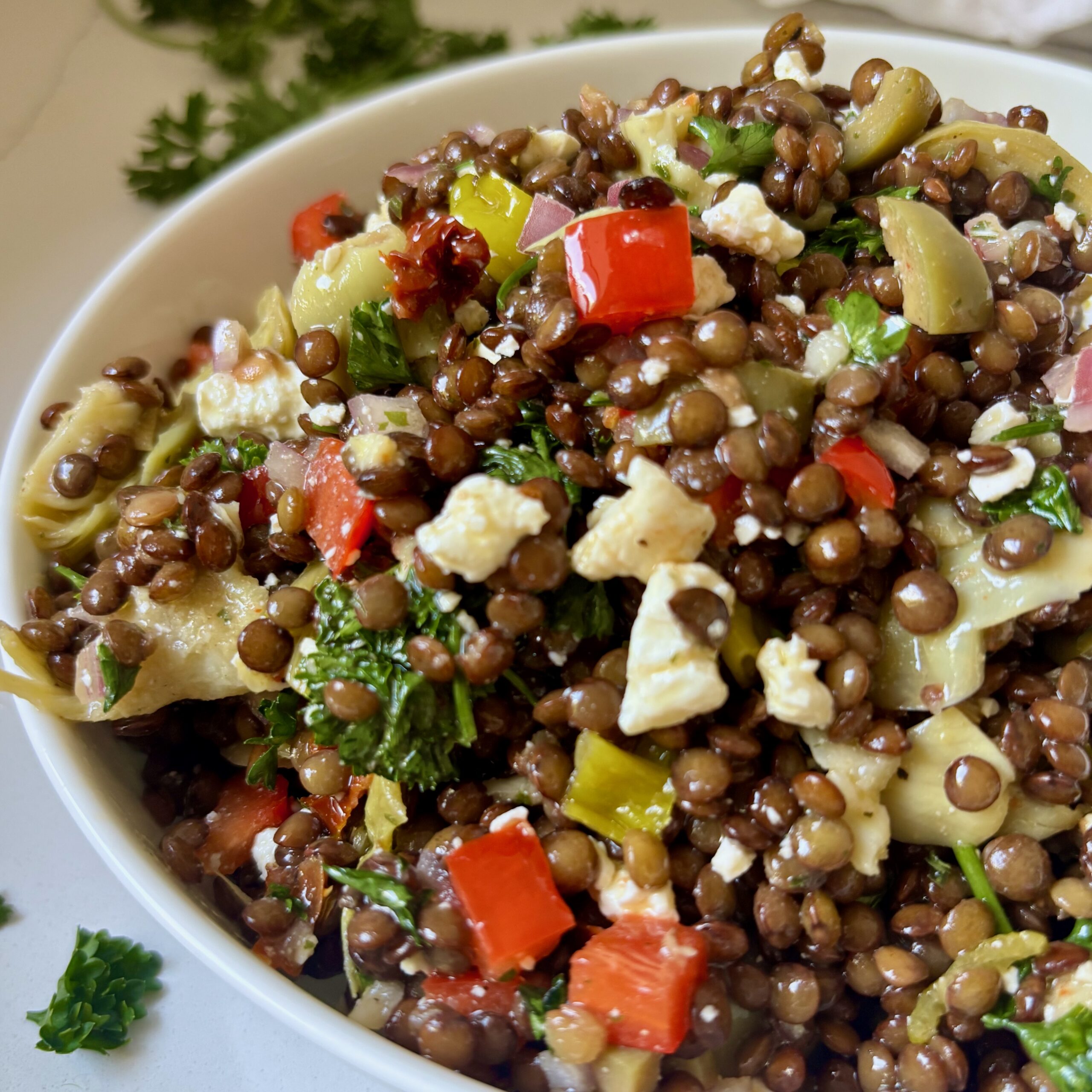 Close up of marinated lentil jar salad with artichokes, red peppers and feta cheese