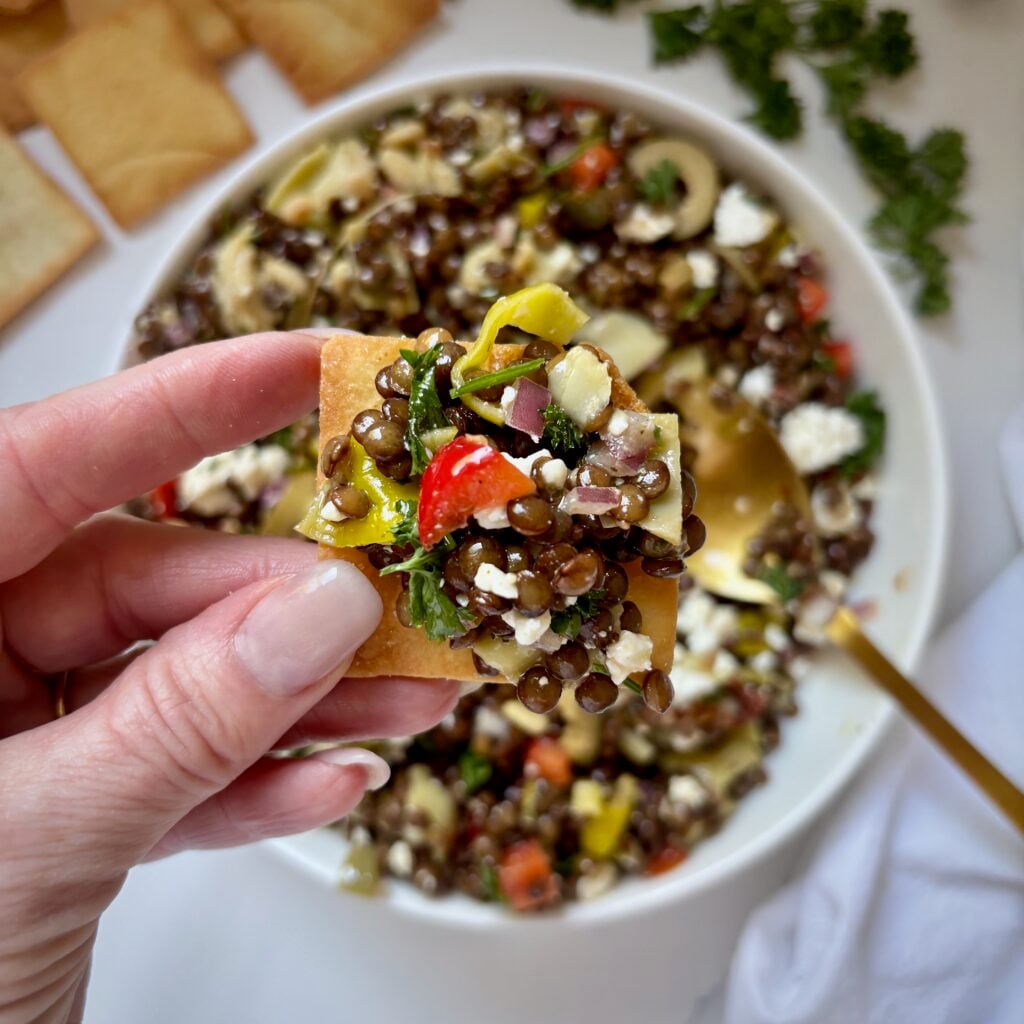 Colourful marinated lentil salad scooped onto a pita chip
