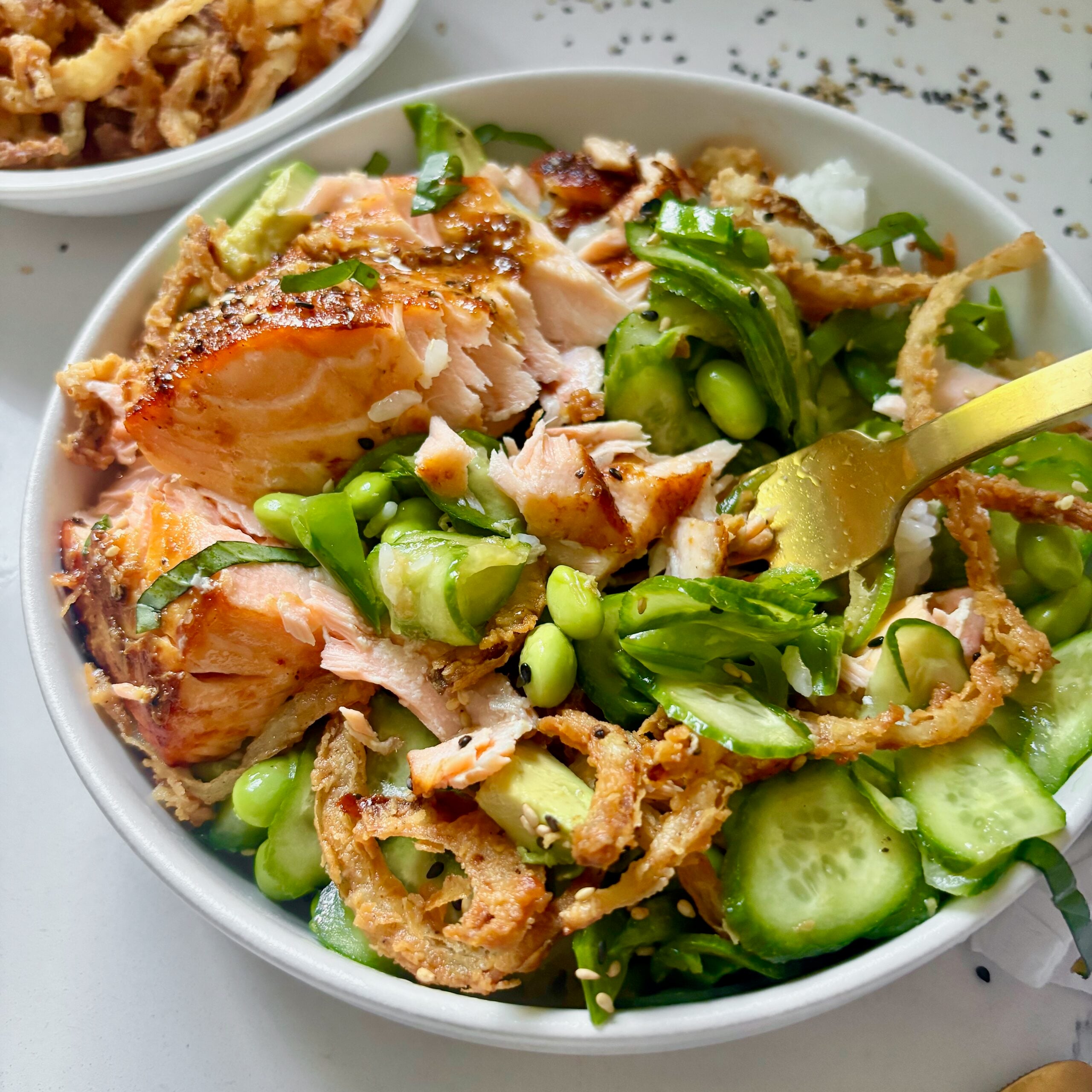 Crunchy salmon rice bowls topped with avocado, crispy onions, and sesame seeds.