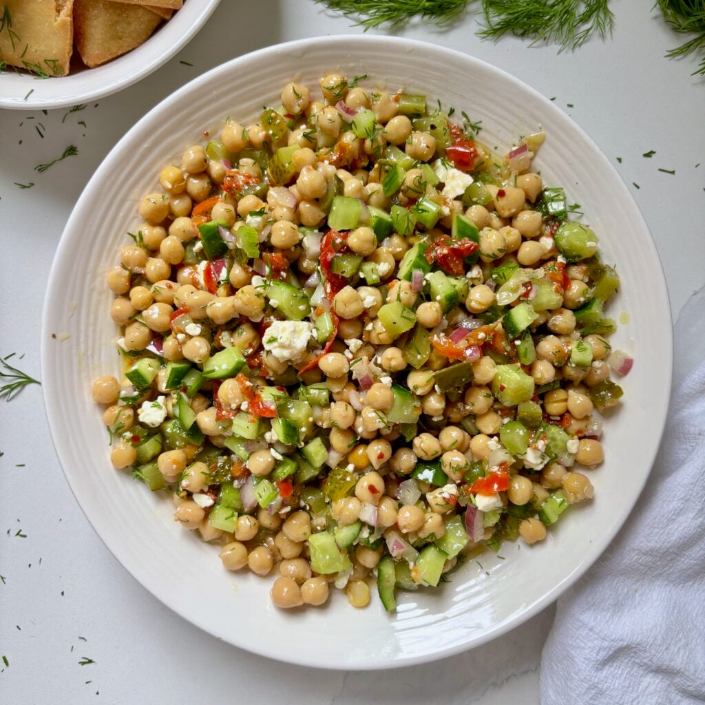 Overhead view of spicy dill pickle chickpea salad served in a white bowl.