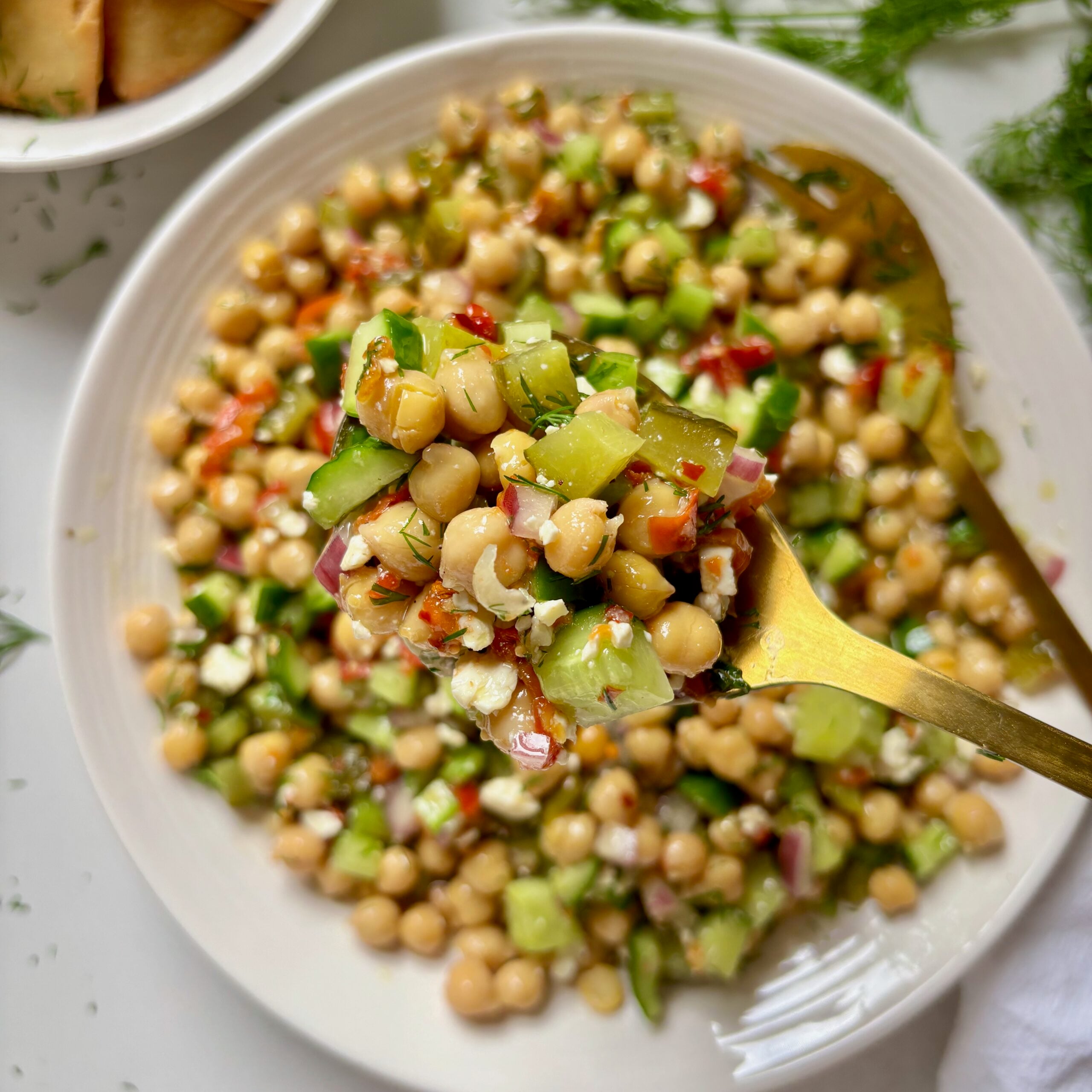 Spoon scooping spicy dill pickle chickpea salad with crunchy vegetables.