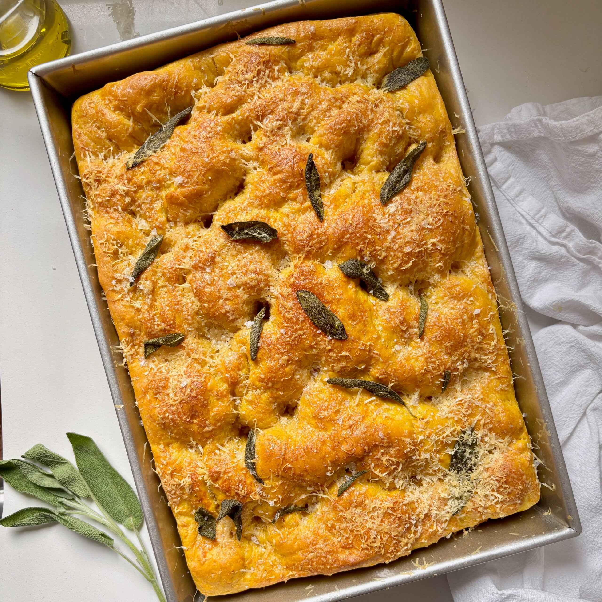 Chewy pumpkin focaccia topped with crispy sage leaves and melted Parmesan