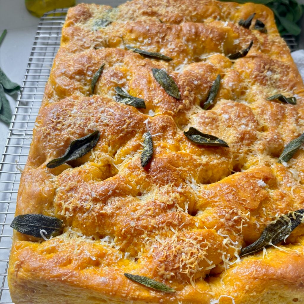 Close-up of fluffy pumpkin focaccia with crisp Parmesan and sage topping