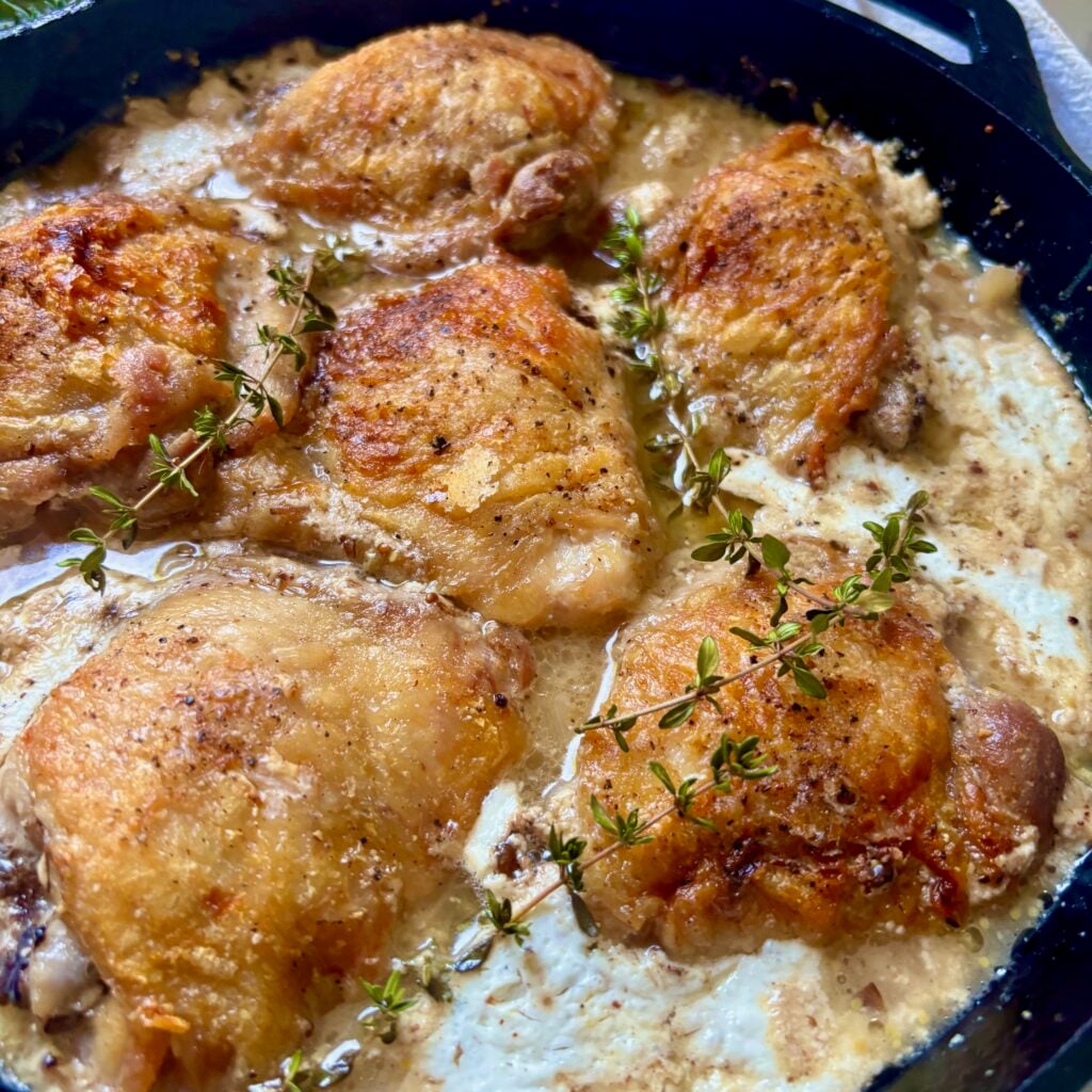 Buttermilk braised chicken thighs with crispy skin, Dijon and fresh thyme in a cast iron pan
