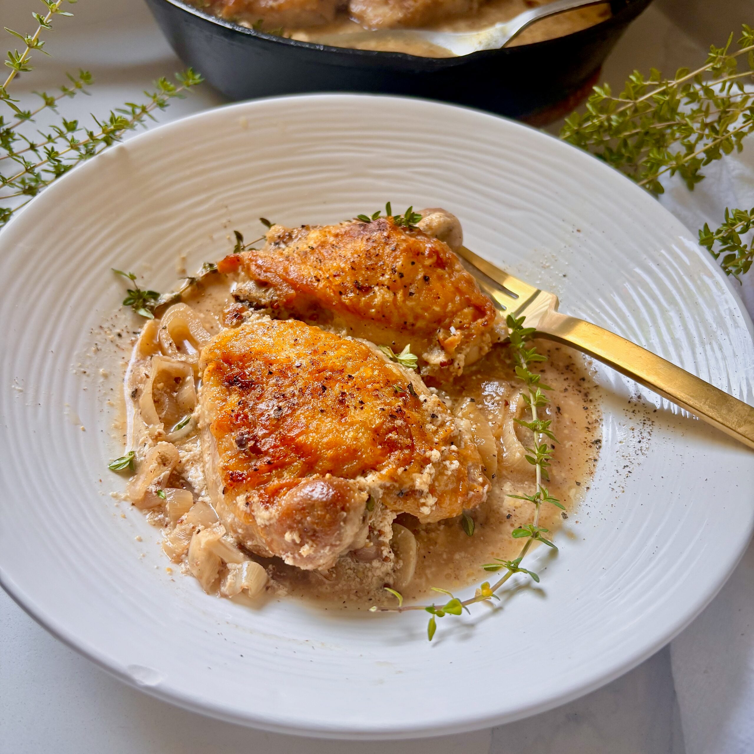 Close-up of crispy-skinned chicken thigh with buttermilk Dijon sauce and fresh thyme