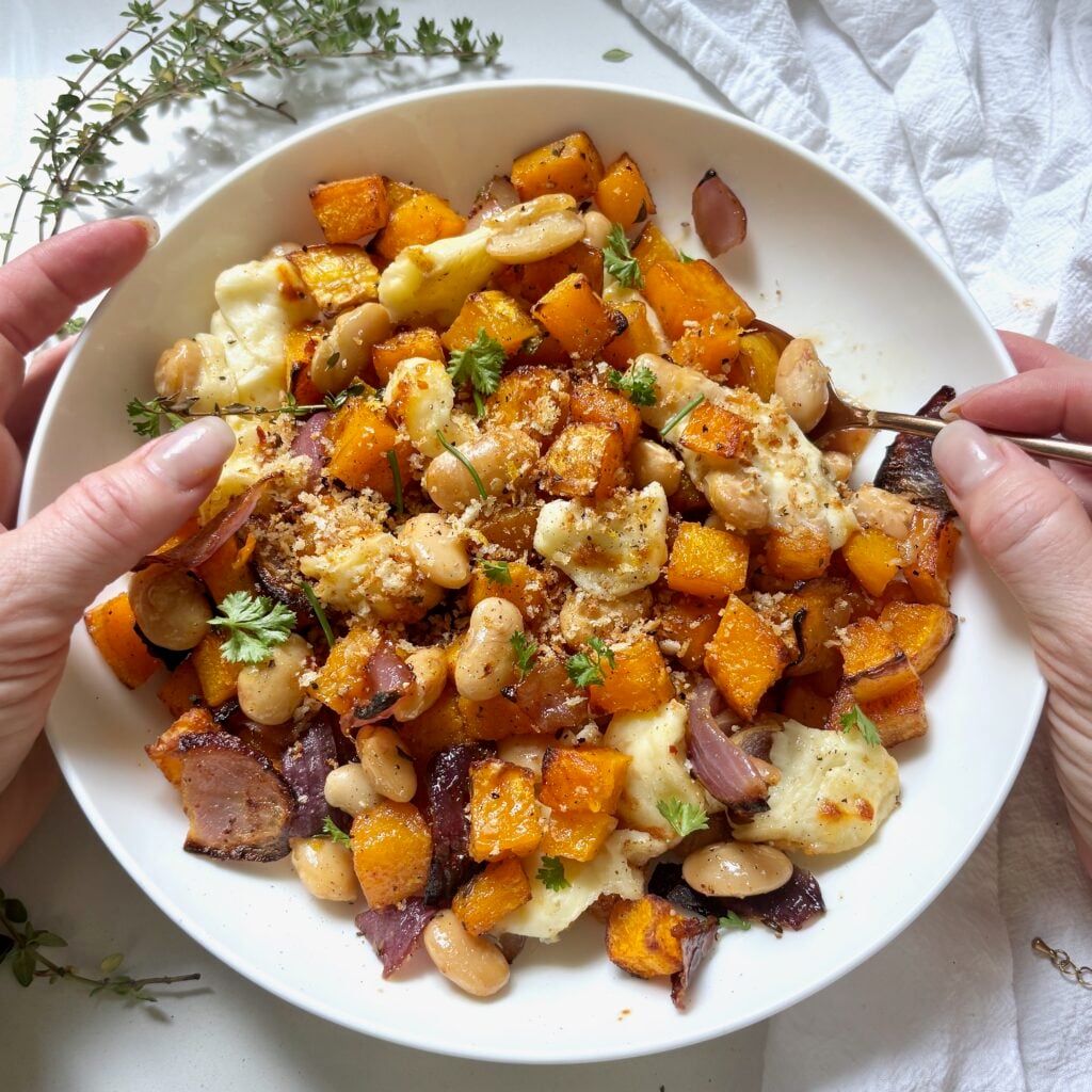 Bowl of butternut squash with golden halloumi and crispy butter beans topped with white balsamic hot honey and lemon garlic panko