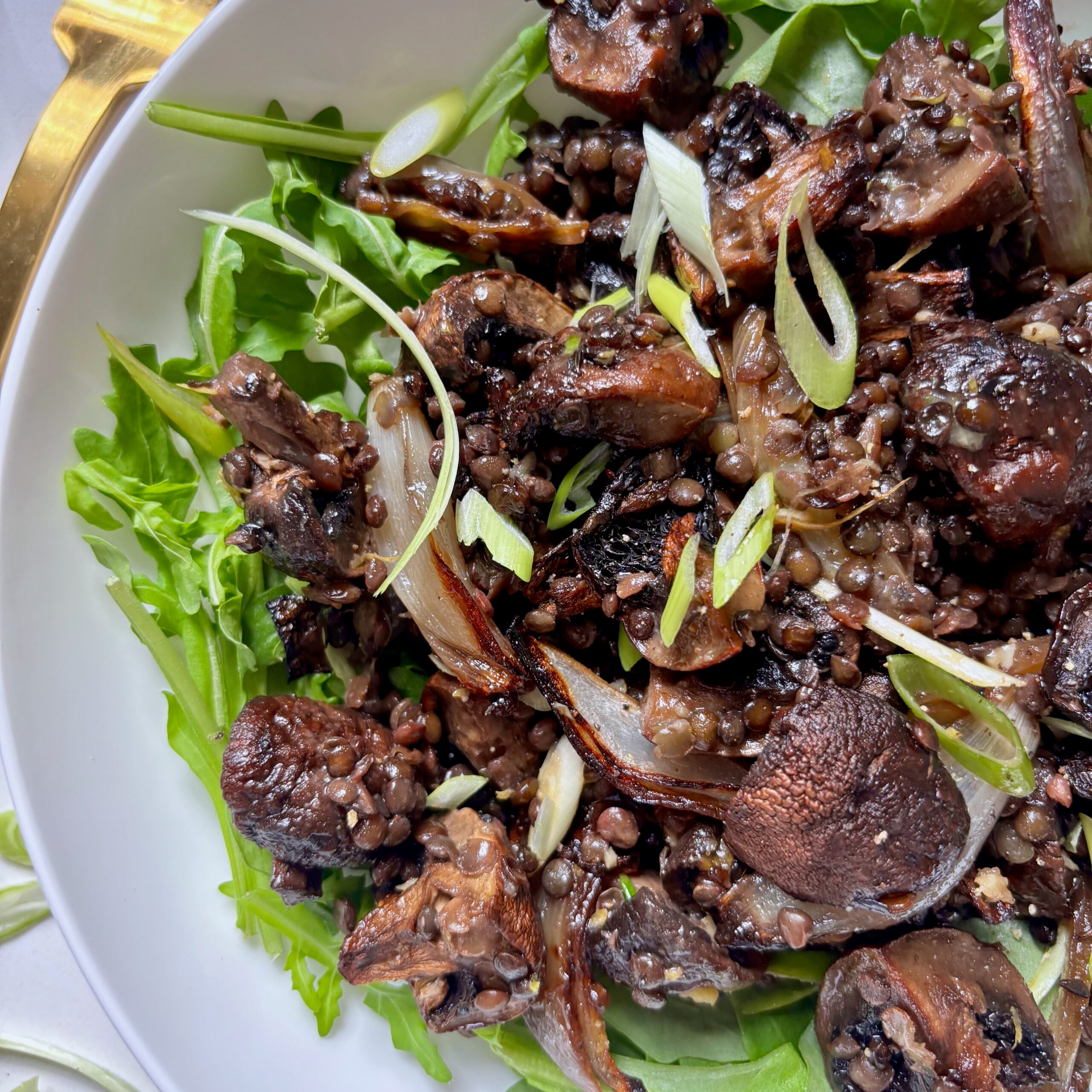 Close-up of golden roasted mushrooms and crispy beluga lentils coated in savoury miso butter sauce.